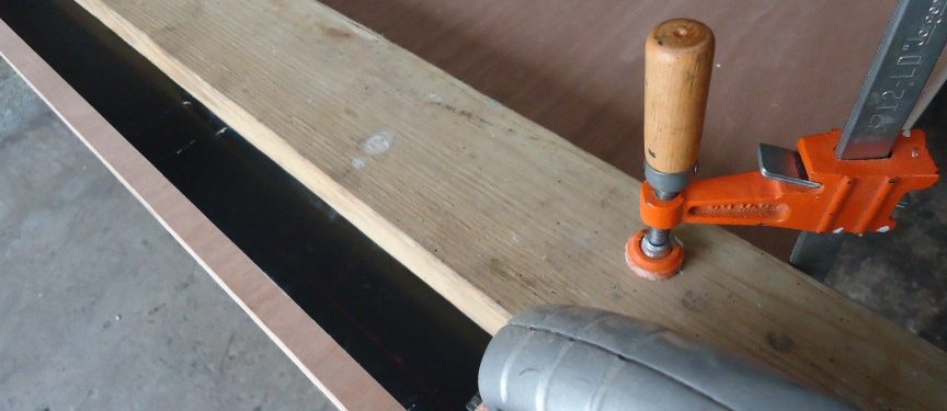 Werkbank-Detail: Massivholzbalken, Schraubzwinge und Handkreissäge